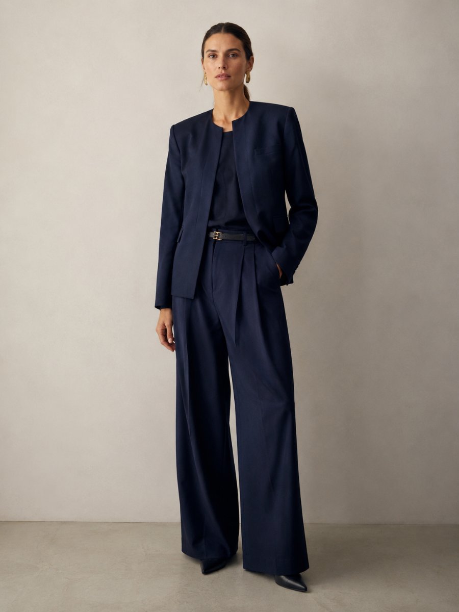 Woman in a collarless blazer over a knit with wide-leg trousers