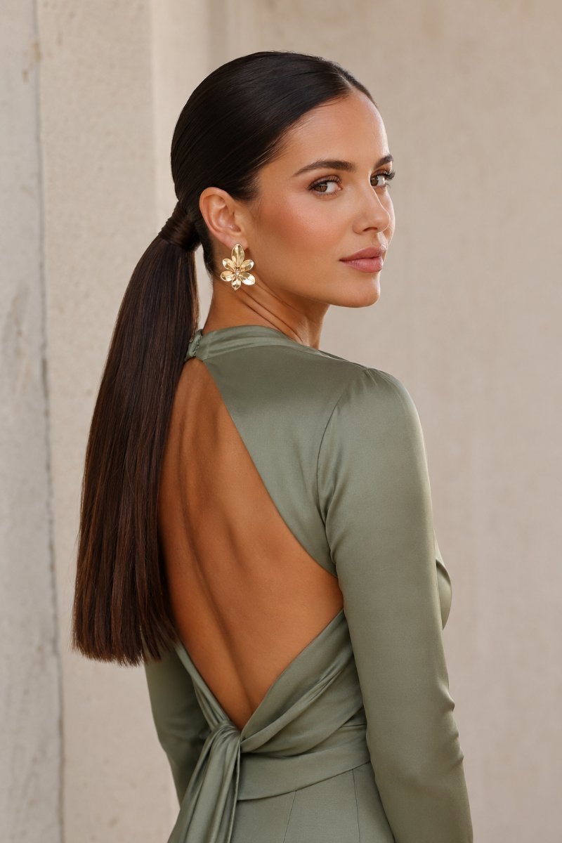 Woman with a sleek glossy low ponytail, elegant wedding guest style