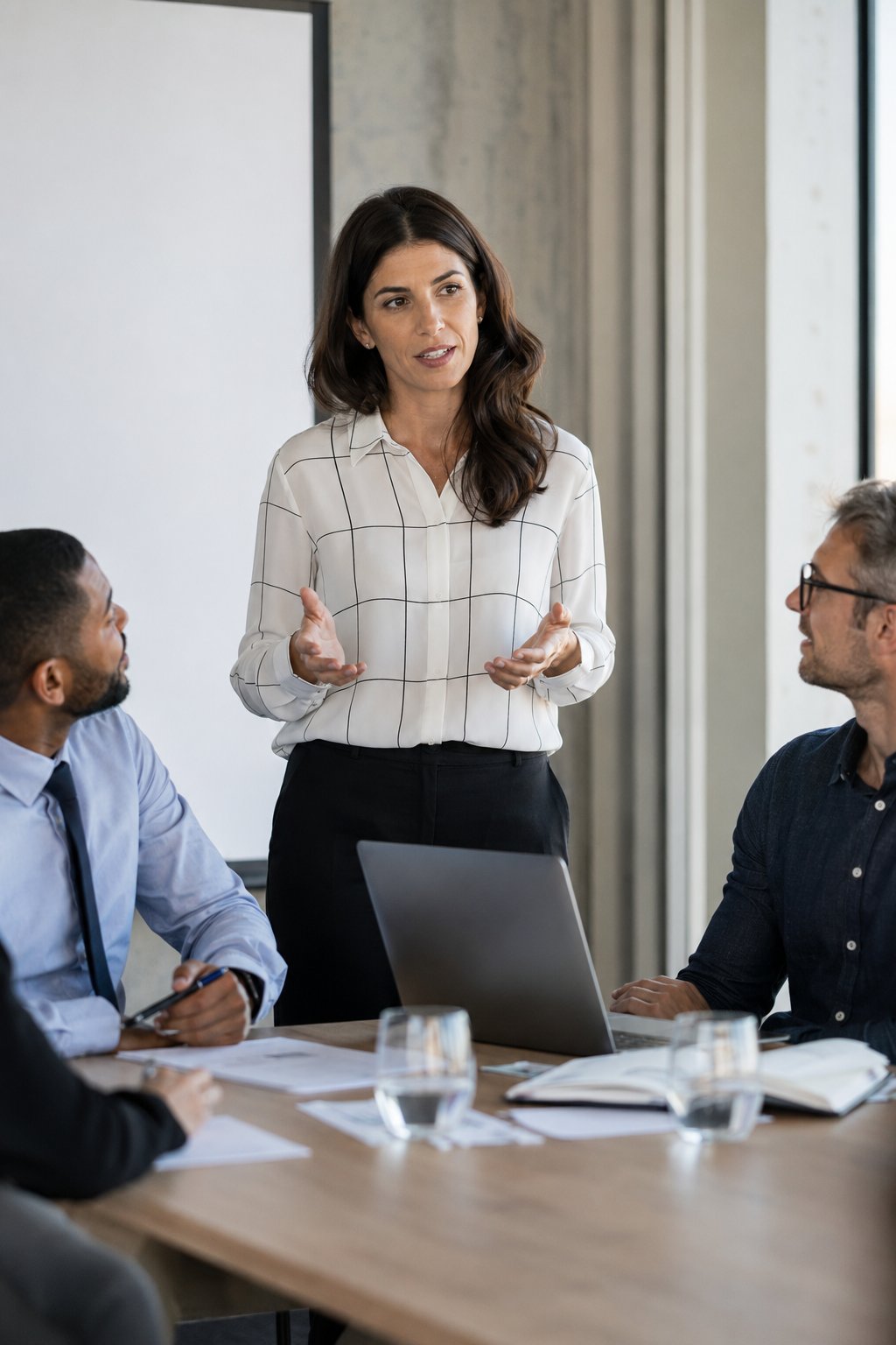 Composed professional woman speaking calmly in a small work meeting